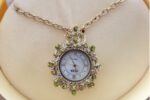1928 Jewelry Gold Tone Chain Necklace Pendant Watch with Light Green Stones and Genuine Mother of Pearl Face